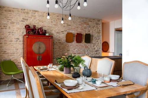 Elegant dining room at Villa Figue Blanche with brick walls, wooden table, and red Asian cabinet in Montagny-les-Buxy.