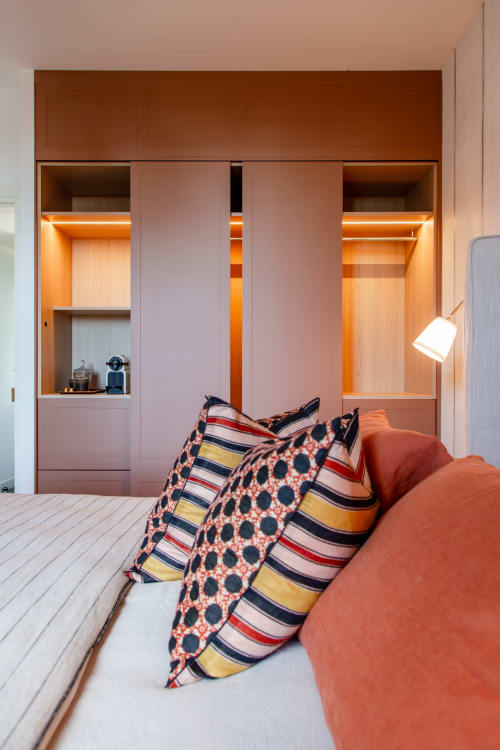 Suite Roche Dorée at Villa Figue Blanche with orange accent lighting, striped pillows, and built-in wardrobe storage.