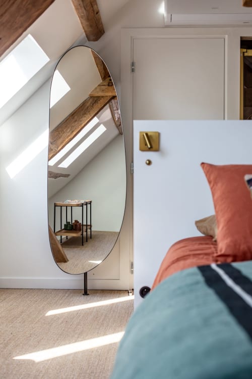 Modern bedroom at Villa Figue Blanche with oval mirror, wooden beams, and coral bedding