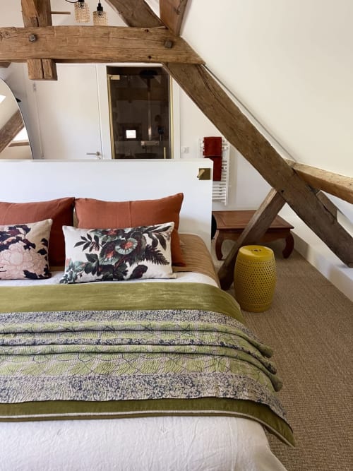 Rustic attic bedroom at Villa Figue Blanche with exposed beams, green bedding, and floral pillows