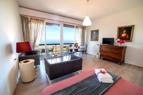Rosa Suite a Belvedere del Lago, Montefiascone: camera con biancheria rosa, balcone con vista lago, zona living con divano e TV
