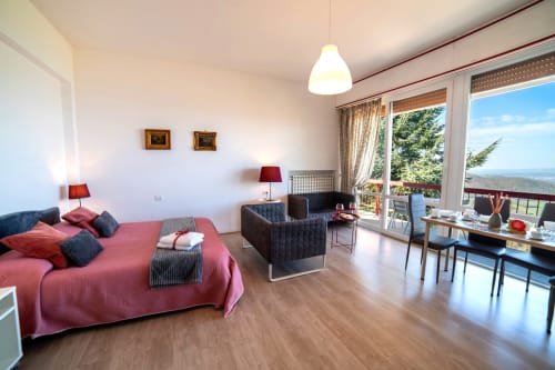 Rosa suite with lake view at Belvedere del Lago, Montefiascone. Pink sofa, modern furnishings, balcony overlooking lake.