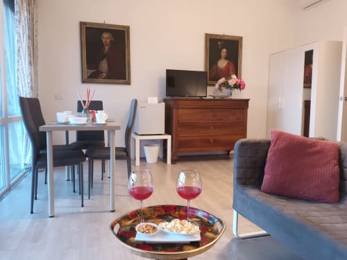 Rosa Suite at Belvedere del Lago: elegant living room with lake view, wine glasses, wooden furniture, and modern amenities in