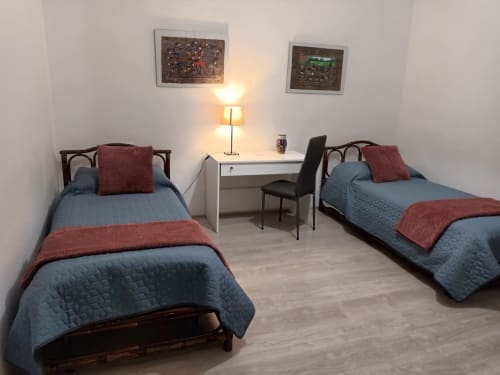 Twin bedroom at Belvedere del Lago with blue quilts, wooden beds, shared desk, and lamp in Montefiascone