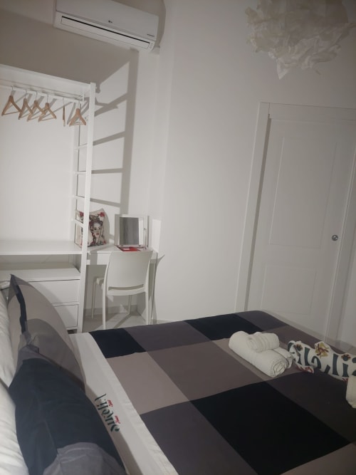 Camera moderna a Sikelia House Cefalù con letto rigato, scrivania, climatizzatore a muro e arredi bianchi