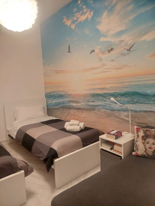 Camera moderna di Sikelia House Cefalù con murale tramonto sul mare, biancheria a righe e arredamento costiero