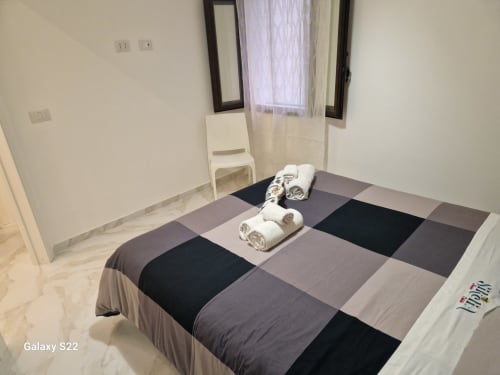 Camera moderna a Sikelia House Cefalù con letto patchwork, asciugamani arrotolati e arredamento minimalista