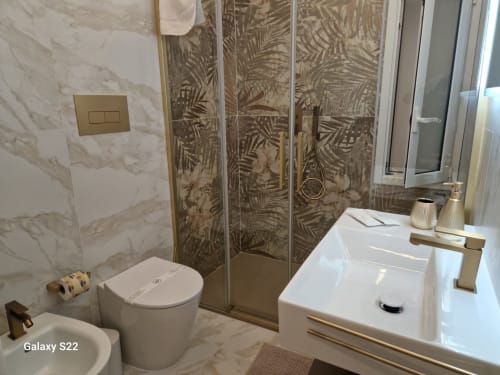 Bagno moderno di Sikelia House Cefalù con rivestimenti in marmo, box doccia in vetro e arredi contemporanei