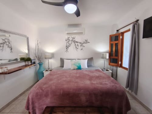 Acogedora habitación en Casa Punta Perula Boutique Hotel con ropa de cama borgoña, ventilador de techo y comodidades modernas en Punta Perula,