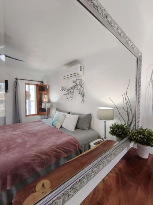 Dormitorio moderno con ropa de cama borgoña y cabecero gris en Casa Punta Perula, con espejo ornamental y unidad de aire acondicionado