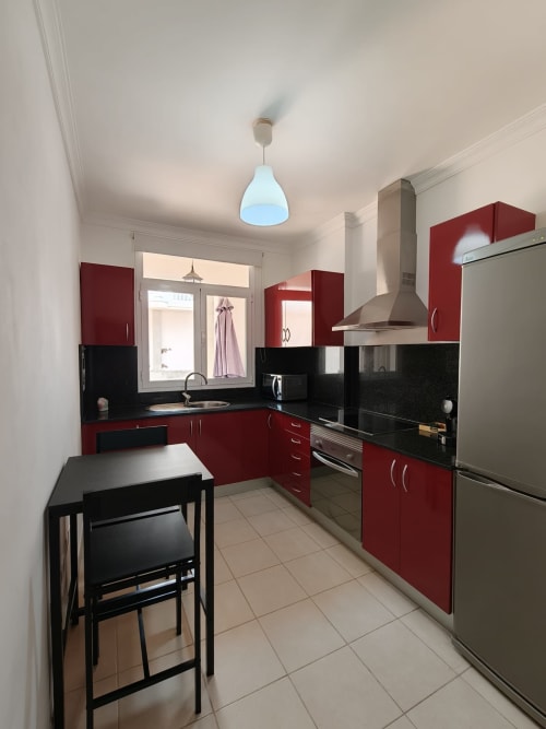 Cocina moderna roja y negra en apartamento Bahia Mar Canarias, Telde con electrodomésticos de acero inoxidable
