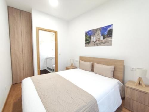 Quarto moderno na SM Stays Collection em Guarda com mobiliário em madeira, roupa de cama branca e casa de banho privativa