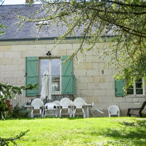 Terrasse en pierre de La Maison Du Saule avec chaises blanches et volets verts, Faverolles sur Cher