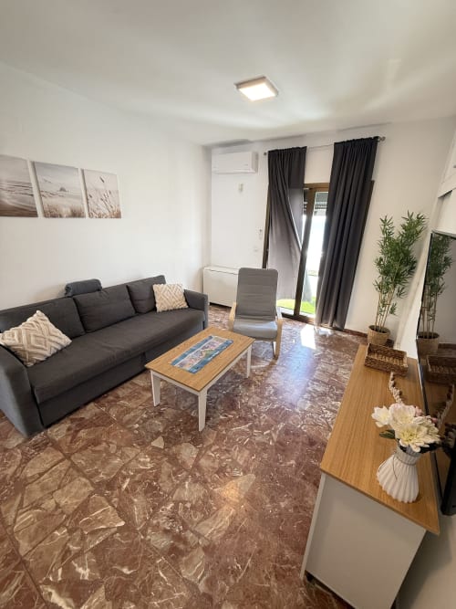 Moderna sala de estar en el Apartamento 7 de Apartamentos A la Orilla del Mar, Matalascañas, con sofá oscuro, pisos de mármol y