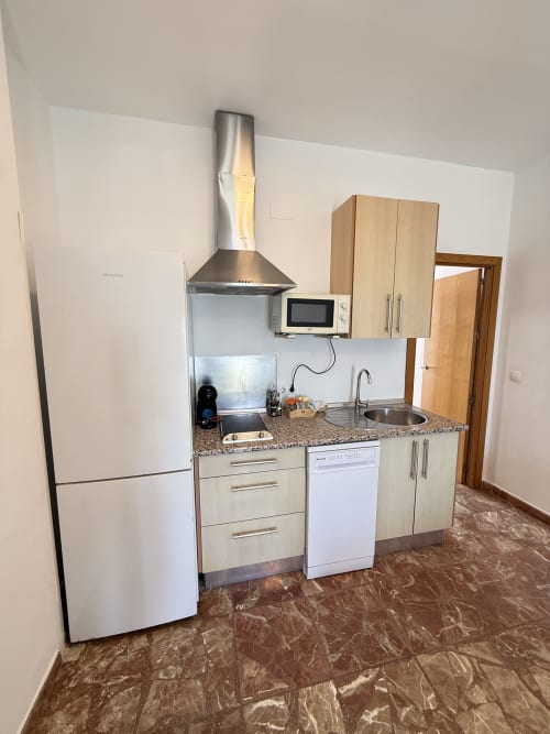Cocina moderna en apartamento de Matalascañas con electrodomésticos de acero inoxidable, encimera de granito y campana extractora