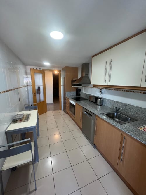 Cuisine moderne de l'appartement Sant Jordi avec comptoirs en granit, appareils en acier inoxydable et carrelage