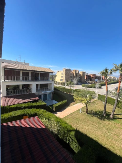 Complexe d'appartements Sant Jordi avec bâtiments modernes, jardins paysagés, palmiers et vue sur les montagnes