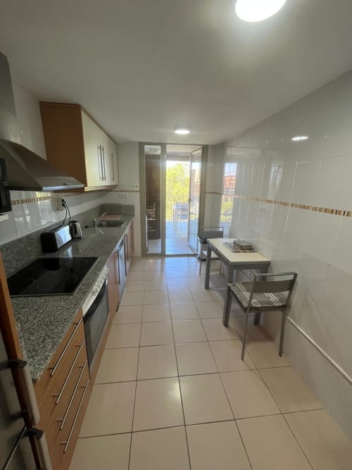 Cuisine moderne à Sant Jordi avec comptoirs en granit, table à manger et accès balcon avec vue sur les montagnes