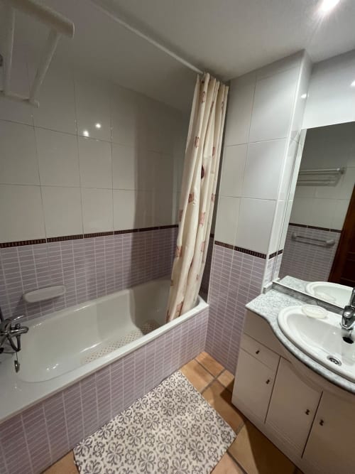 Salle de bain moderne de l'appartement Sant Jordi avec baignoire, douche, double vasque et carrelage rose