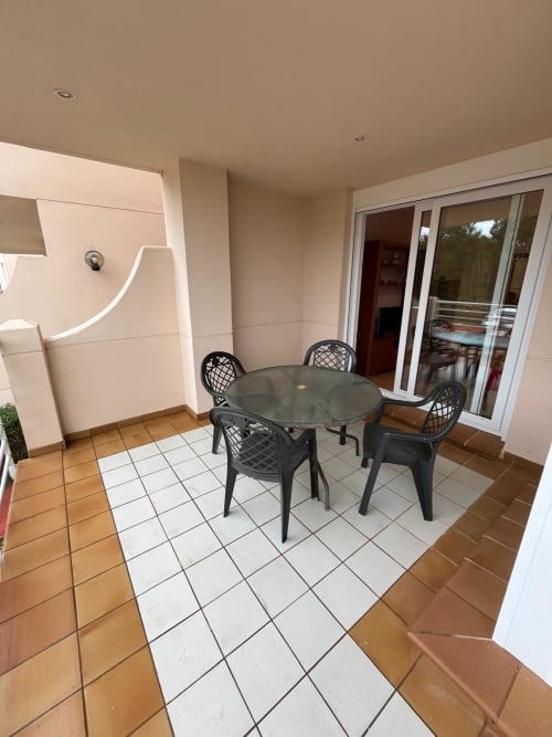 Patio couvert avec table ronde et chaises noires dans un appartement 2 pièces avec vue sur le golf à Sant Jordi, Espagne