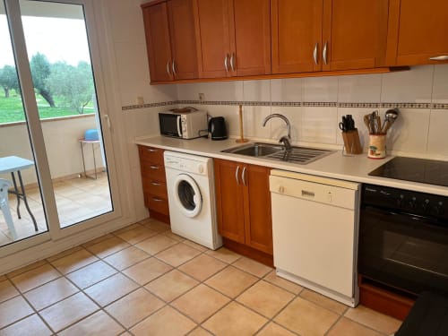 Cuisine moderne avec meubles en bois, appareils en acier inoxydable et carrelage en terre cuite dans l'appartement Sant Jordi avec jardin