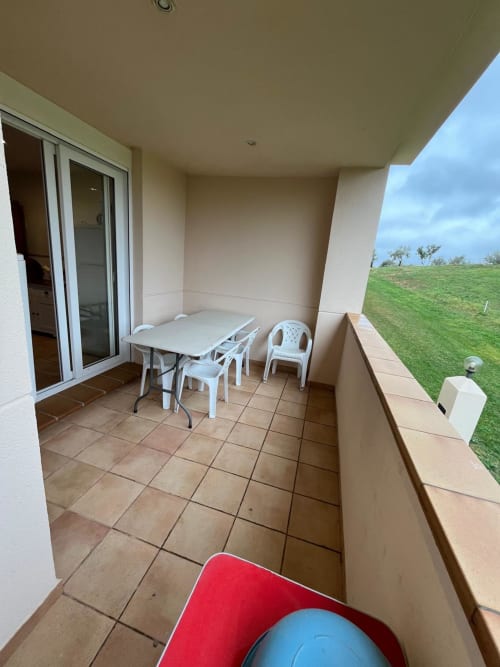 Balcon couvert avec table à manger et chaises offrant une vue panoramique sur le parcours de golf verdoyant de l'appartement Sant Jordi