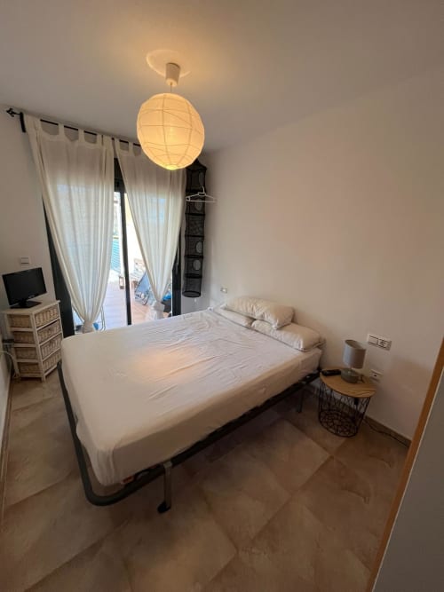 Chambre moderne de l'appartement Golf Mar à Sant Jordi avec lit, luminaire suspendu, accès à la terrasse, TV et vue sur le jardin