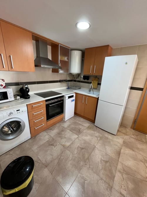 Cuisine moderne de l'appartement Golf Mar 4 avec armoires en bois, électroménagers blancs et revêtement carrelé chez Home Guardian Services
