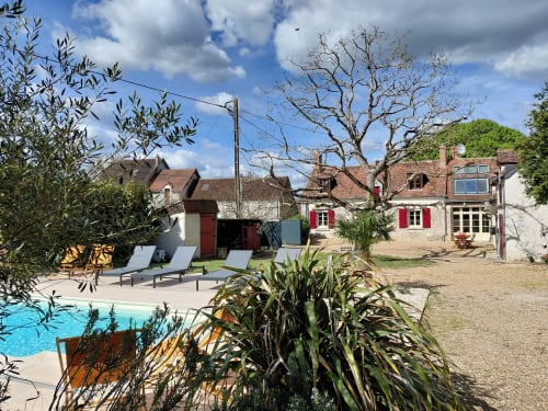 Cortile con piscina e lettini presso i Gîtes au fil des châteaux de la Loire, tra storici edifici in pietra della Valle della Loira