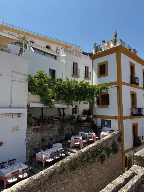 Charming courtyard at Hotel La Ventana in Ibiza with white and golden-yellow buildings, dining terrace, and climbing ivy