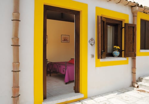 Luminoso ingresso giallo di una camera presso l'Agriturismo Sirignano Wine Resort a Monreale, Sicilia