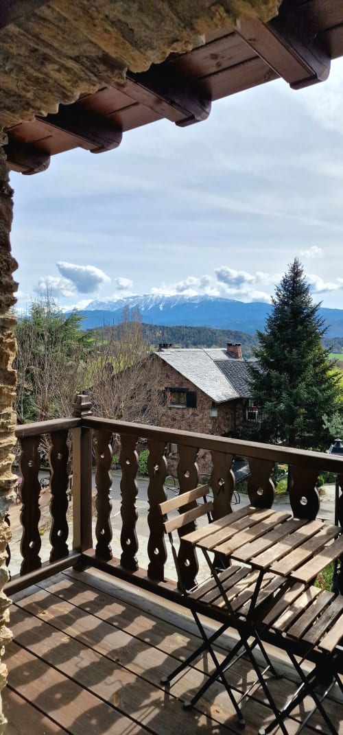 Vista desde el balcón de la habitación Deluxe del Hotel Mas D'En Roqueta con montañas nevadas, caserío rural y barandilla de madera