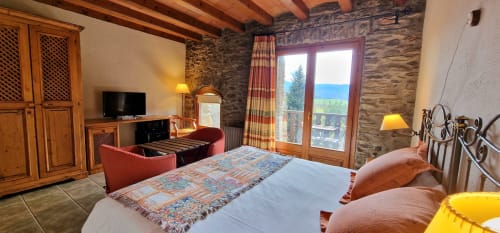 Lujosa habitación doble con muros de piedra, vigas de madera y vistas panorámicas desde balcón en Hotel Mas D'En Roqueta, España