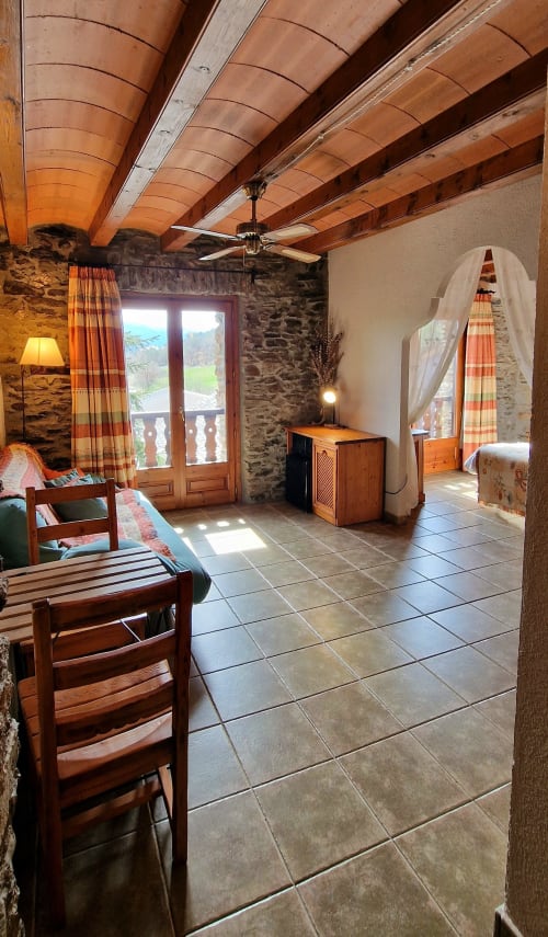 Habitación doble espaciosa en Hotel Mas D'En Roqueta con vigas de madera, paredes de piedra, techo de barro y vistas al paisaje
