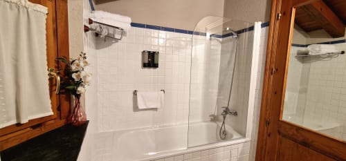 Baño moderno con ducha a ras de suelo, azulejos blancos, marcos de madera y toallas frescas en Hotel Mas D'En Roqueta