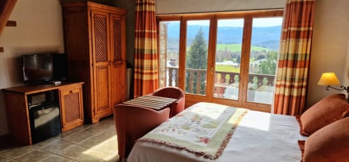 Habitación doble deluxe con balcón en Hotel Mas D'En Roqueta, mobiliario de madera, vistas a la montaña y acceso a terraza