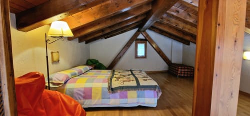 Acogedor dormitorio abuhardillado en Hotel Mas D'En Roqueta con vigas de madera vista, dos camas y decoración rústica en España