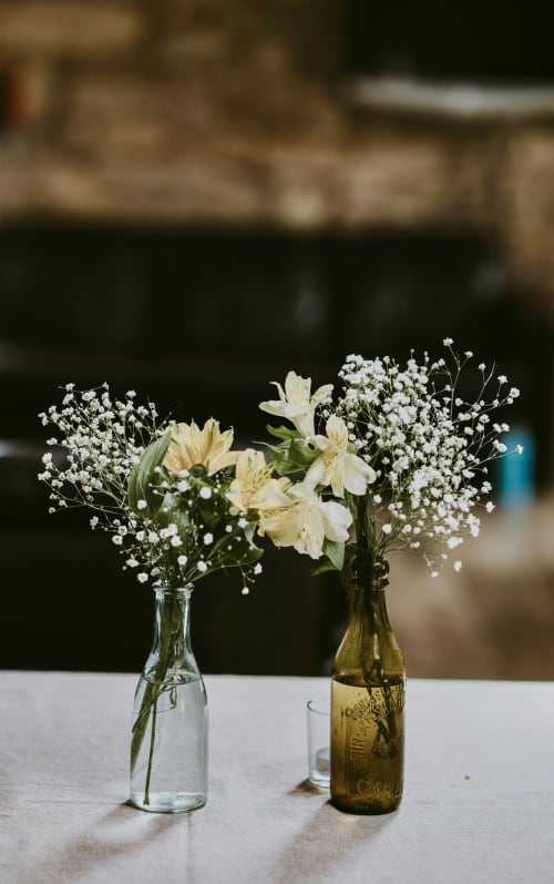 Fleurs crème délicates et gypsophile dans des bouteilles transparentes et ambrées à la boutique B&B La Ferme 1828 à Megève