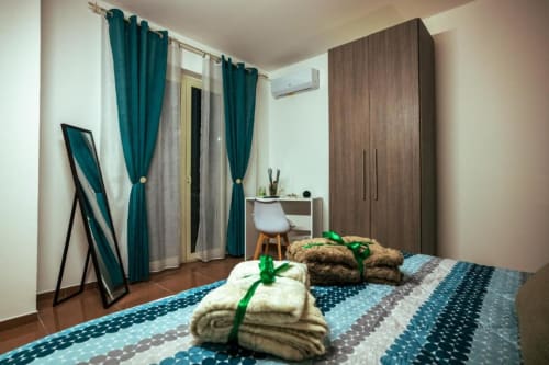 Grecale Room at Torre dei Venti BnB in Ceccano, featuring double bed with folded towels, teal curtains, wooden wardrobe,