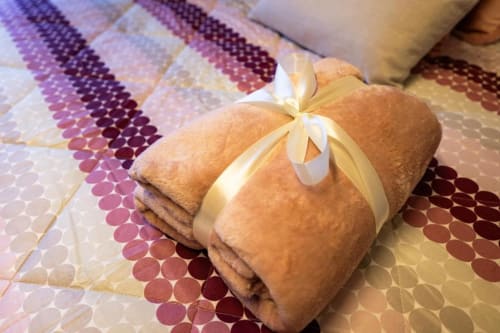 Asciugamani marrone arrotolati con fiocco nastro crema su tappeto decorativo nella Suite Libeccio, Ceccano
