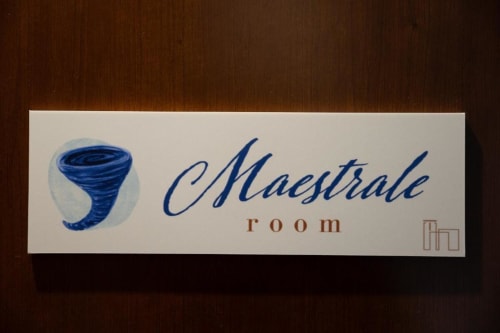 Mistral Room nameplate at Torre dei Venti bed and breakfast in Ceccano, Italy, featuring blue tornado logo design on cream