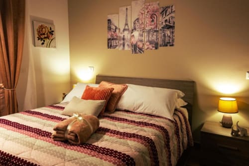 Camera Libeccio presso Torre dei Venti B&B a Ceccano - accogliente camera da letto con vista sul giardino, biancheria a righe bordeaux e calda atmosfera
