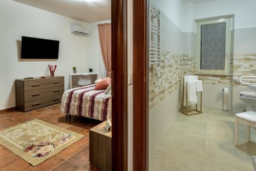 Stanza Libeccio della Torre dei Venti B&B a Ceccano: letto, comò, TV e bagno ensuite moderno con doccia piastrellata.