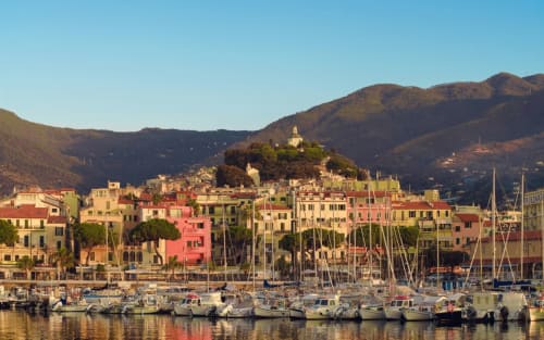 Porto di Sanremo colorato con barche a vela, edifici storici e montagne presso Sally's Case Vacanze