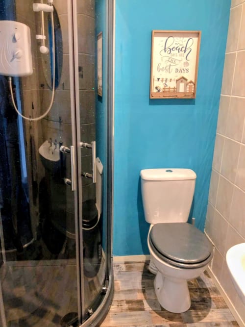 Modern bathroom in Seashell Suite at Commodore B&B, Rothesay, with turquoise walls, shower cubicle, and beach-themed decor