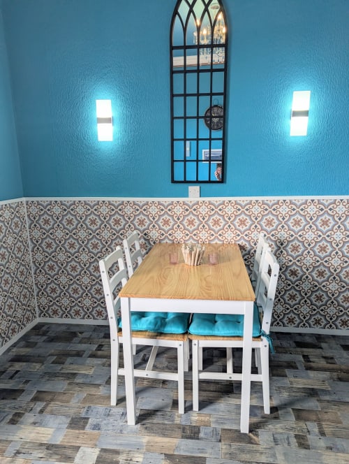 Dining area in Seashell Suite at Commodore B&B, Rothesay, with wooden table, white chairs, turquoise wall, patterned tiles,