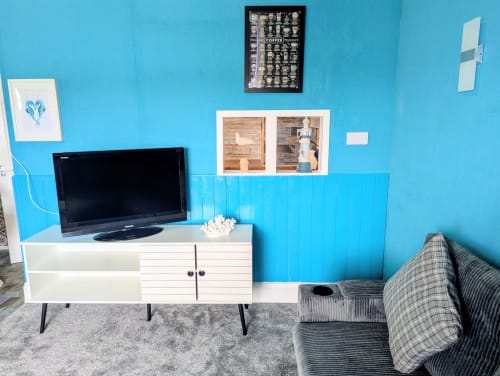 Bright turquoise living room in Seashell Suite at Commodore B&B, Rothesay, featuring white TV unit, flat-screen TV, patterned