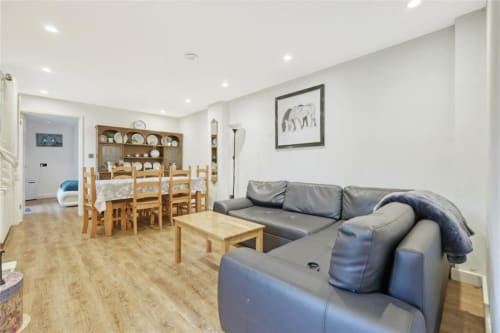 Modern open-plan living area at Blackbrook Cottages with gray sofa, dining table, wooden chairs, and kitchen in background