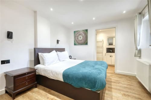 Modern bedroom at Blackbrook Cottages in Colchester with double bed, en-suite bathroom, and wooden flooring