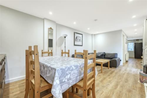 Open-plan apartment at Blackbrook Cottages with wooden dining table, bed, sofa, kitchen, and modern amenities in Colchester.